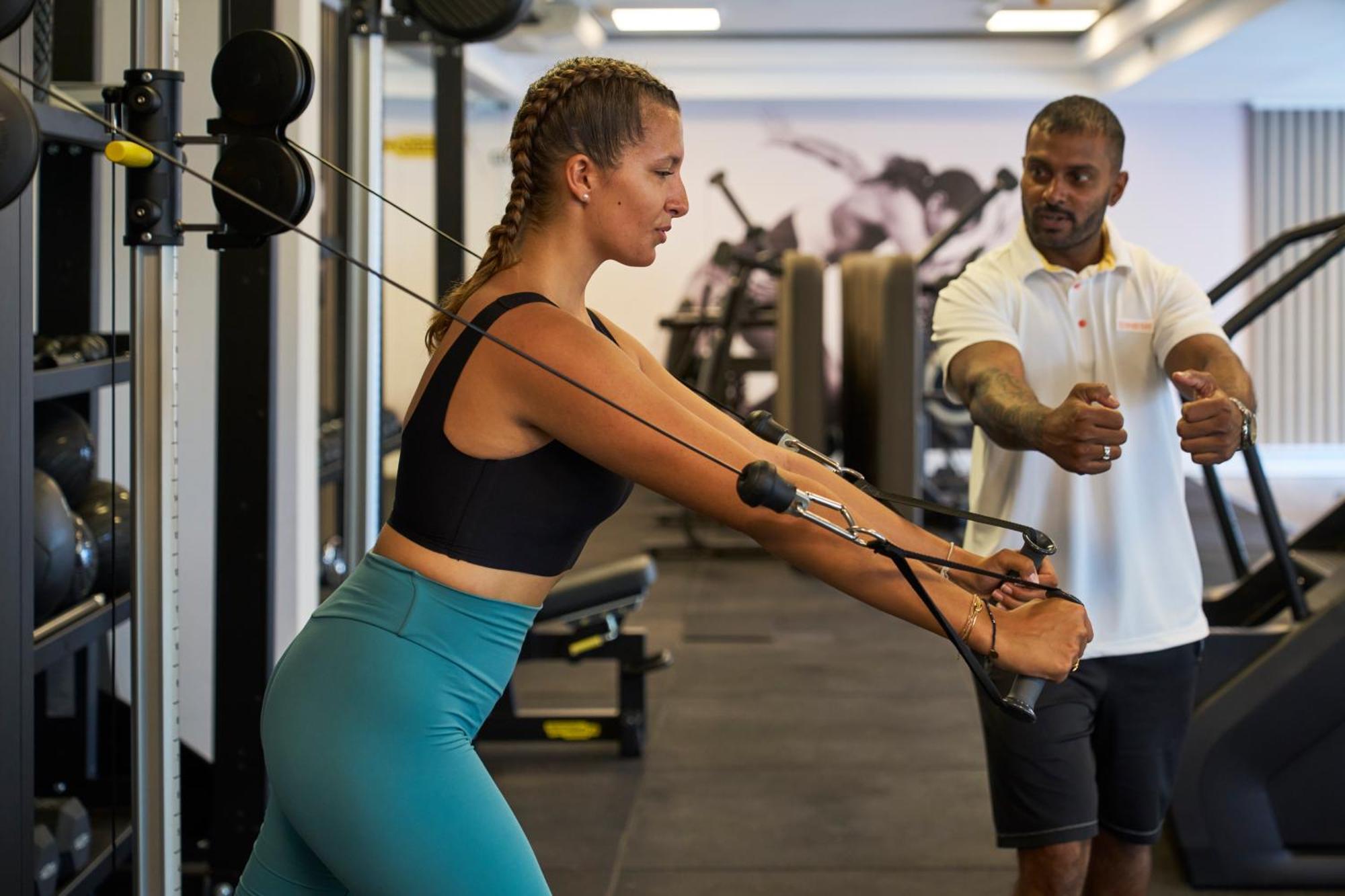 LUX* Belle Mare Resort&Villas Esterno foto Personal trainer assisting a woman with a cable row exercise
